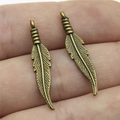 Paar antieke bronzen veerhangers voor DIY sieraden maken vastgehouden in de hand - Antiek Brons