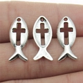 Three antique silver Ichthys fish charms with hollow cross design on human fingers - Antique Silver