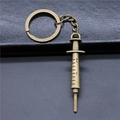 Vintage bronze syringe pendant keychain with realistic scales on dark leather background - Antique Bronze
