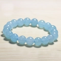 Detail shot of 10mm light blue chalcedony beaded bracelet on a light wood background - Blue Chalcedony