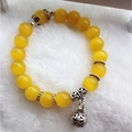 Detailed shot of yellow synthetic cat eye beads with vintage silver bell pendant charm - 10mm / Yellow