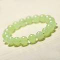 Polished light green chalcedony beaded bracelet on a minimalist wooden background - Grape Chalcedony