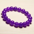 Close-up of a purple beaded chalcedony bracelet on a warm light wood texture surface - Dark Purple Chalcedony