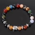 Detailed view of colorful volcanic stone beads and silver Buddha head on black reflection - Multicolor Agate