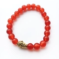 Gros plan de perles d'agate rouge avec breloque bouddha dorée sur bracelet élastique - Style Bouddha Or en Jade Rouge