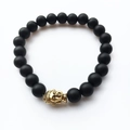 Détail macro des perles en pierre de lave noire mate et du charme de Bouddha doré sur le bracelet - Style Bouddha Or en Noir Mat