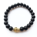 Macro view of vintage black agate beads and a golden Buddha head on the energy bracelet - Black Agate Gold Buddha Style