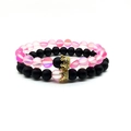 Detail of couple bracelets featuring matte black and iridescent aurora beads with gold crowns - Pink Combo