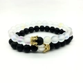 Detail of matte black and iridescent white bead bracelets with gold crown charms - White Combo