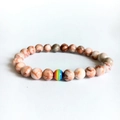 Kralenarmband met marmertextuur en een regenboogaccent op witte ondergrond - Rode Netwerksteen