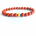 Ronde rode agaat kralen armband met een centrale regenboog gestreepte kraal in focus - Rode Jaspis
