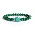 Detail of green malachite beads with a light blue turtle charm on an elastic bracelet - Malachite