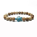 Macro detail of elastic beaded bracelet with brown marble stones and a blue sea turtle charm - Jasper