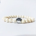 Macro detail of white turquoise stone beads with a silver dog paw charm bracelet - Howlite