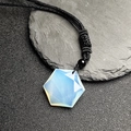 Macro shot of hexagonal opal stone pendant with black braided rope on dark slate - Opal