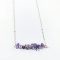 Close-up of irregular purple amethyst stone pendant on a delicate gold chain necklace - Amethyst