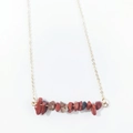 Close-up of red jasper natural stone chips on a minimalist gold link chain necklace - Red Jasper