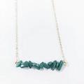Macro detail of natural green irregular stone chips on a minimalist gold necklace - Malachite