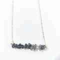 Detail view of irregular dark natural stones on a delicate gold chain necklace - Black Rutilated Quartz