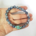Hand holding a blue stone bead bracelet with a turquoise sea turtle charm - Blue Spot Jasper