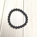 Macro detail of polished 8mm black agate stone beads on a minimalist elastic bracelet - Black Onyx