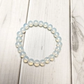 Macro shot of 8mm milky white opal beads bracelet with translucent texture on wood background - Opal