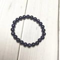 Close-up of 8mm blue sand stone beaded bracelet with starry glitter on wood background - Blue Sandstone