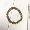Macro shot of 8mm tiger eye stone beads on a stretch bracelet with polished texture - Yellow Tiger Eye