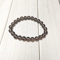 Close-up of translucent dark brown agate stone beads on a white wooden background - Smoky Quartz