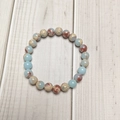 8mm natural stone beaded stretch bracelet with blue and earthy marble patterns on wood - Emperor Stone