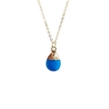 Detailed close-up of a faceted water-drop blue crystal pendant on a gold chain necklace - Synthetic Blue Jade
