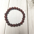 Macro shot of 8mm deep red natural stone beads with smooth texture on wood background - African Jasper