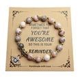 Evil Eye natural stone beaded bracelet with gold spacers on a kraft paper gift card - Pink Zebra Jasper