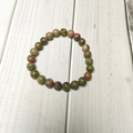 Close-up of 8mm natural Unakite stone beads with unique green and pink textures - Unakite