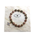 Detail von Rosa Naturstein Evil Eye Armband mit Goldperlen auf Marmor-Hintergrund - Rhodonit mit schwarzen Linien