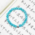 Macro d'une perle Yin Yang et pierres turquoises sur un fond de calligraphie d'art - Turquoise Bleue