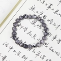 Détail macro du bracelet en perles yin yang avec pierres naturelles noires et blanches sur calligraphie - Pierre de Carte