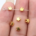 Golden crown spacer beads for jewelry making held by fingers for scale - Antique Gold