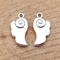 Pair of antique silver wing pendants made of zinc alloy on a natural wood surface - Antique Silver