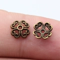 8mm vintage bronze flower bead caps for jewelry making shown on a fingertip for scale - Antique Bronze