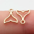 Golden whale tail pendant in hollow design shown on fingertip for size reference - KC Gold