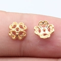 Golden clover filigree bead caps for DIY jewelry making shown on a fingertip - KC Gold