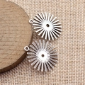 Pendenti a sole geometrici in argento su blocco di legno e sfondo di lino beige - Argento antico