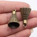 Pair of antique bronze 3D badminton shuttlecock charms held in hand for size comparison - Antique Bronze