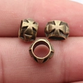 Three vintage bronze cross cylinder beads displayed on finger for size reference - Antique Bronze