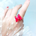 Detail eines goldenen Schmetterlingsrings mit rosaroten Kristallen an der Hand - Einstellbar Offen / Fuchsia