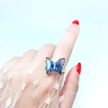 Detailaufnahme eines goldenen Schmetterlingsrings mit blauen Kristallen und Diamanten - Einstellbar Offen / Dunkelblau