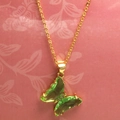 Dettaglio ravvicinato della collana dorata con pendente a farfalla in vetro verde - Verde Mela