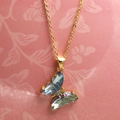 Detailed view of light blue crystal butterfly pendant on a gold link chain necklace - Iridescent Lake Blue