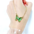Detailed view of a green crystal butterfly pendant with sparkling rhinestones on a gold chain - Apple Green